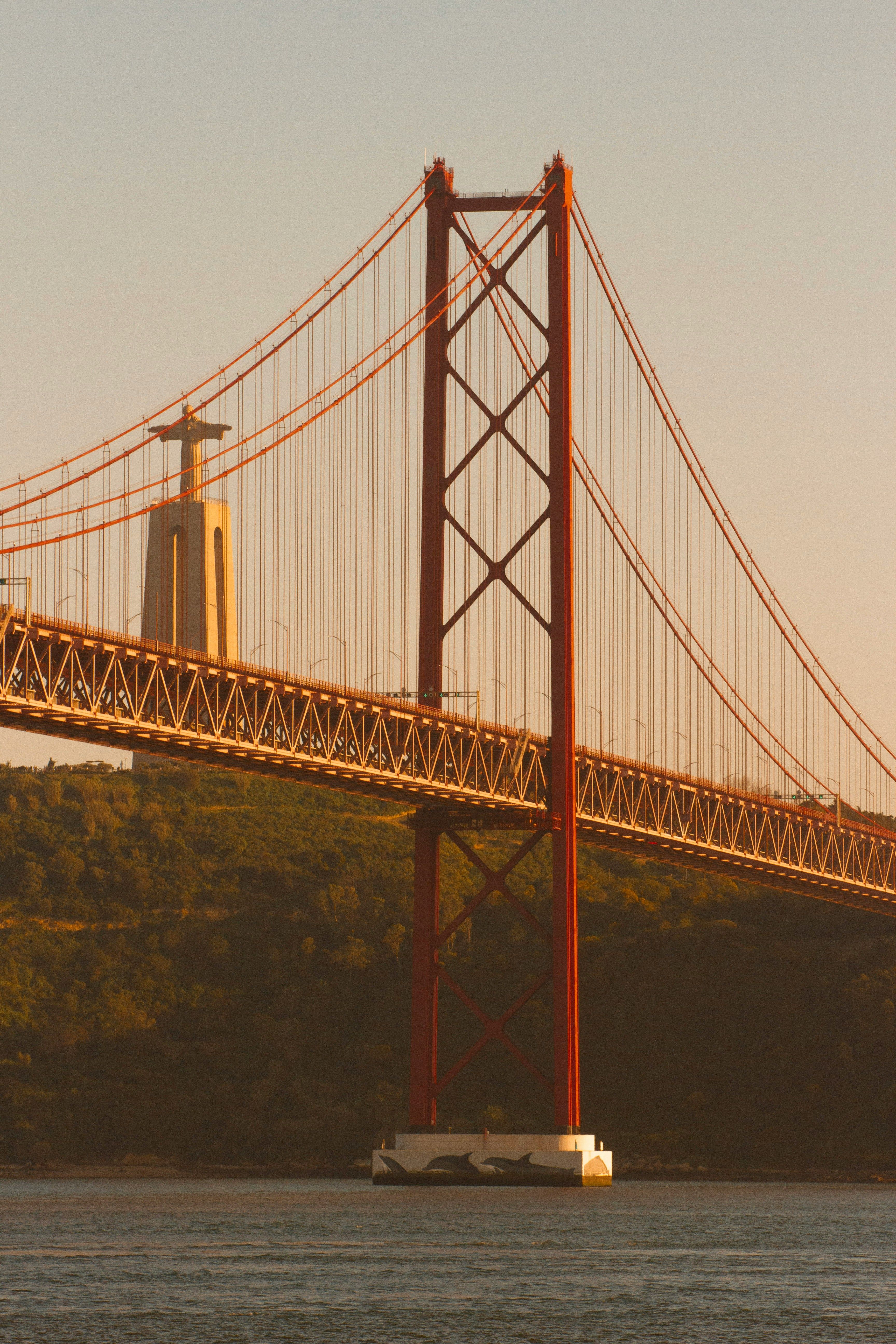 Red 25 de Abril bridge over the Tagus river with a sailboat