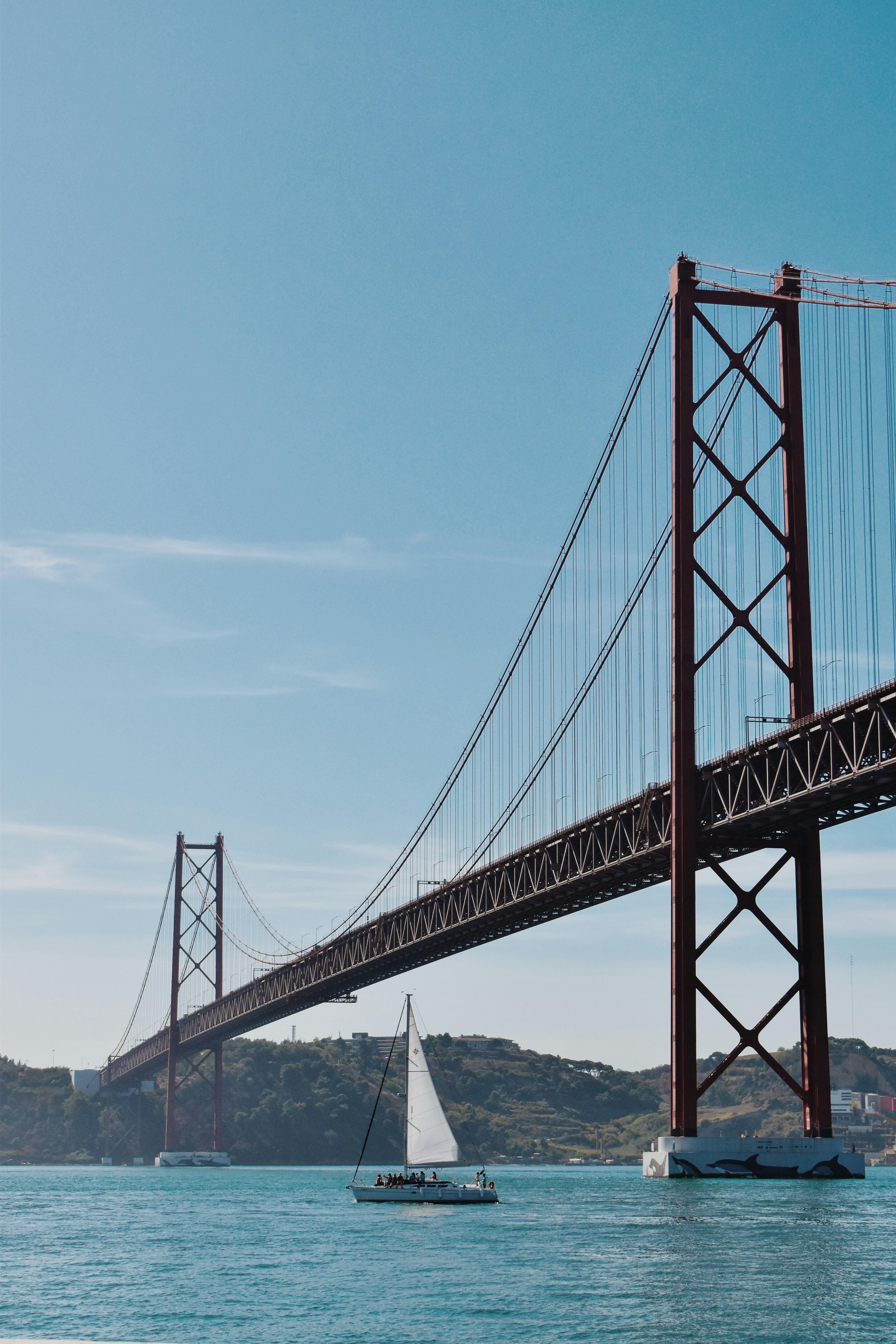 Red bridge over the Tagus river with a sailboat near Cristo Rei