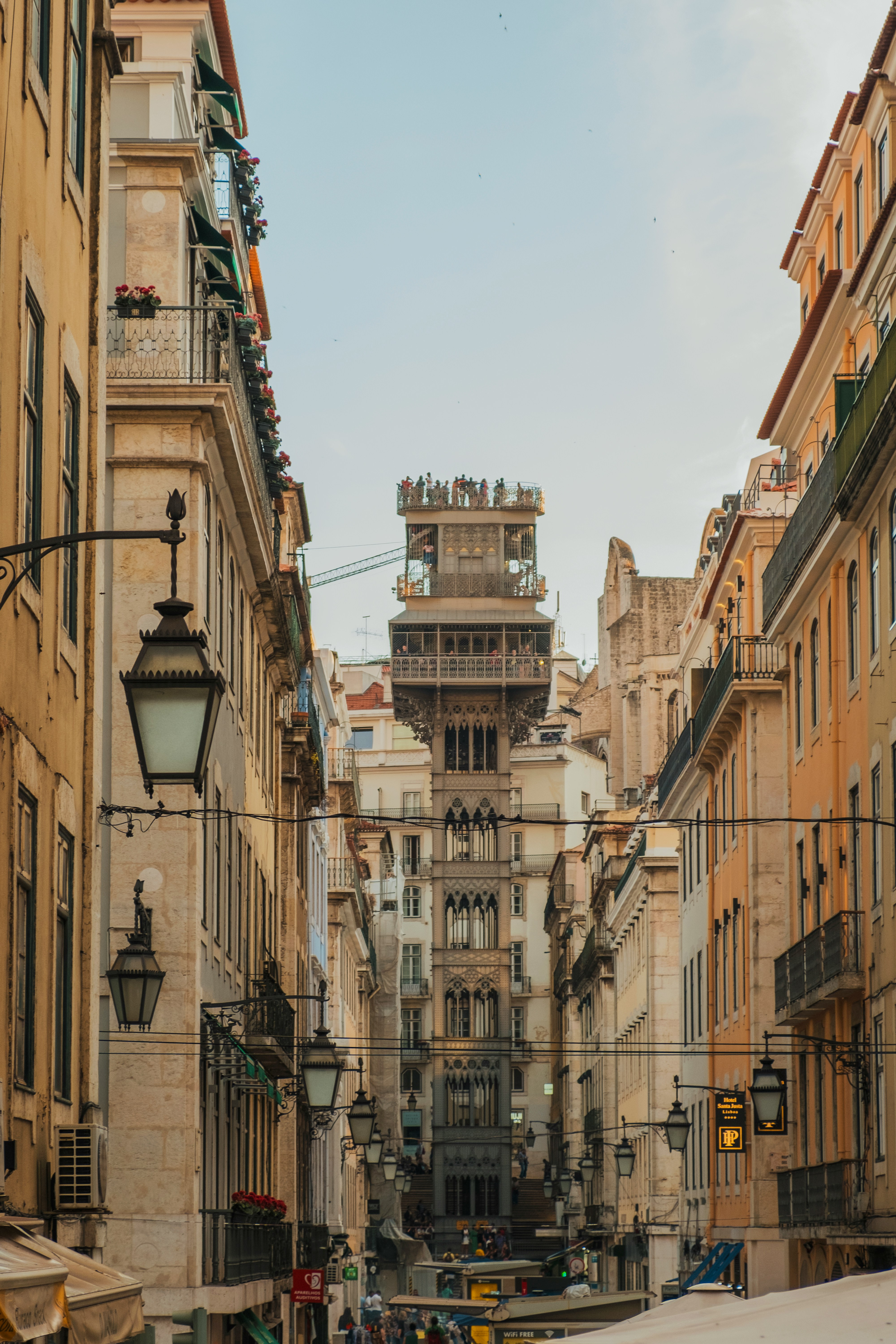 Narrow cobbled Lisbon street with parked cars and a street lamp